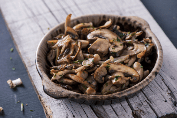 closeup of a brown earthenware bowl with some cooked mixed mushrooms such as common mushrooms oyster mushrooms or shiitake on a white rustic wooden board closeup of a brown earthenware bowl with some cooked mixed mushrooms such as common mushrooms oyster mushrooms or shiitake on a white rustic wooden board
