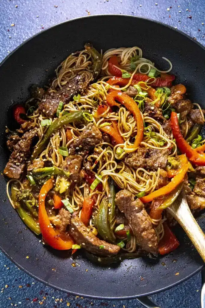 A top view of beef and noodles with stir fry seafood in a pan