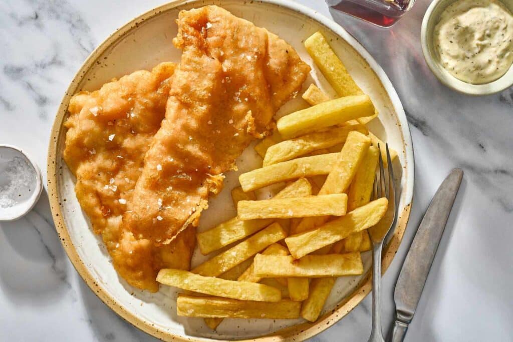 A top view of fish and chips plated out with a fork and knife