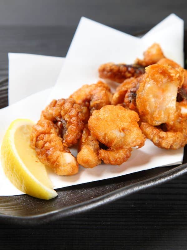 A view of a fried octopus plated out with a sliced lemon