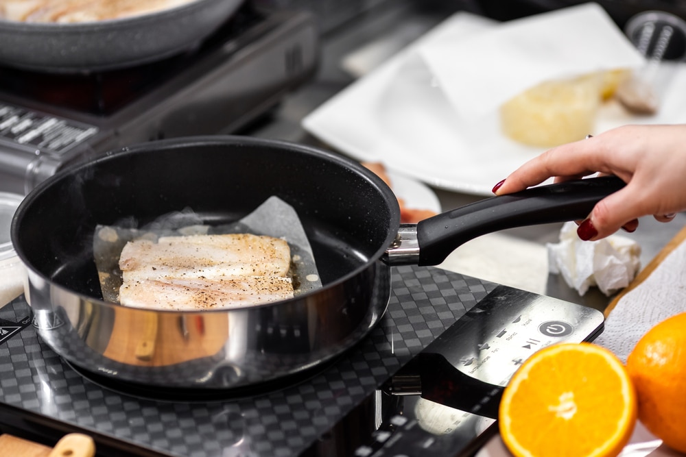 A view of cod fish being fried inside a pan