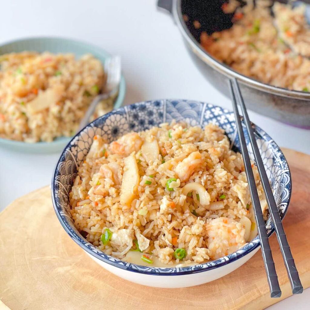 A view of seafood fried rice in a bowl with chopsticks