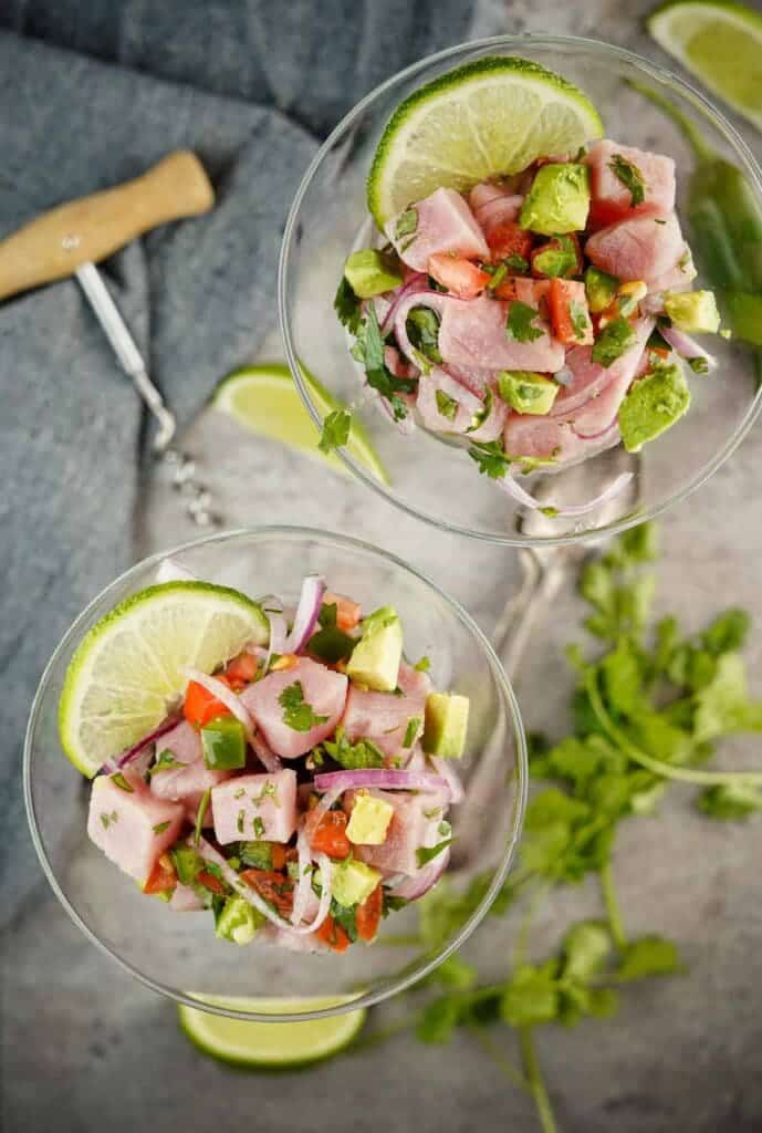 Tuna ceviche in two glasses with lime wedges on top