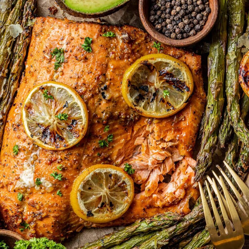 cooked grilled salmon with lime wedges on top forks placed on the side