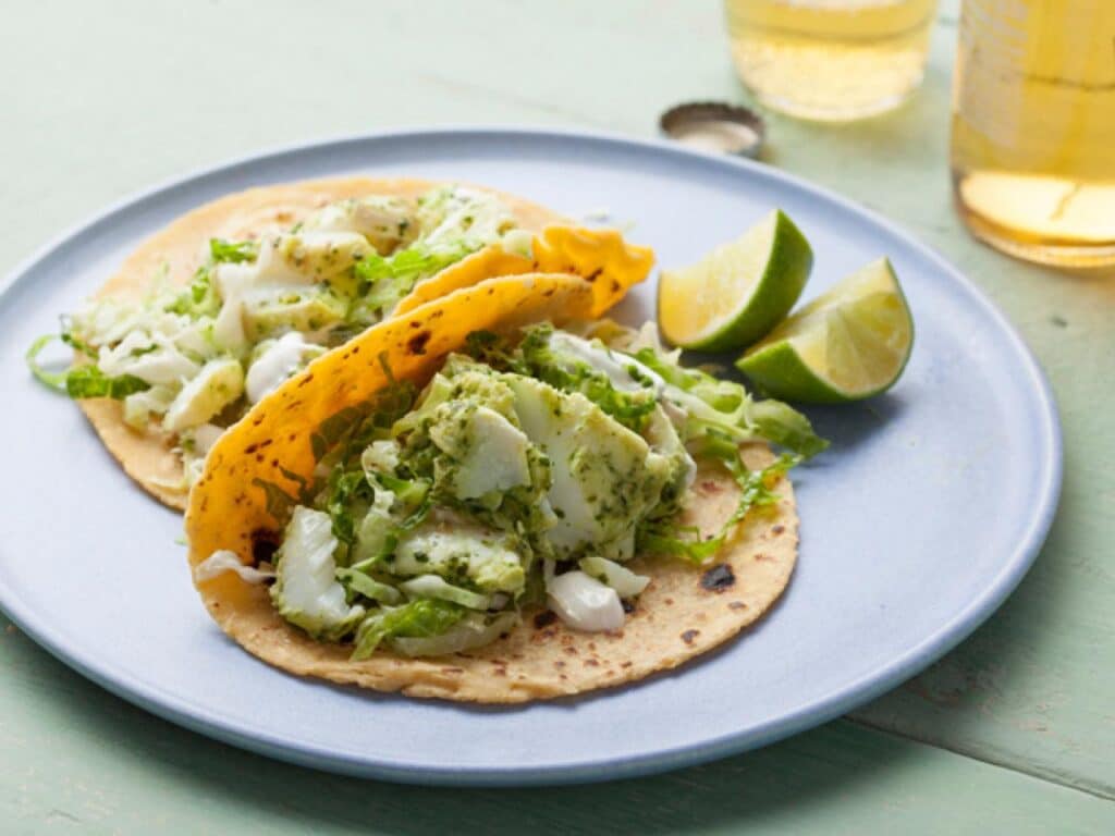 halibut tacos with cilantro and shredded cabbage on the top in a plate