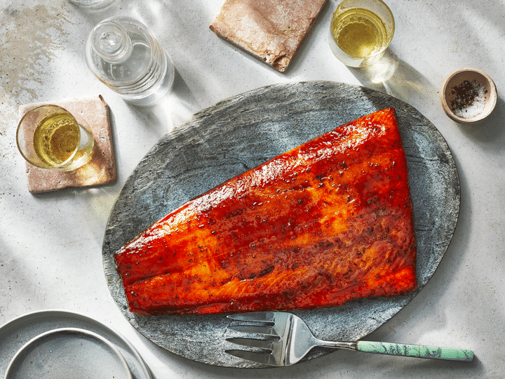 salmon fillets marinated and placed on a wooden tray oil in aglass anwd cup spices in a bowl