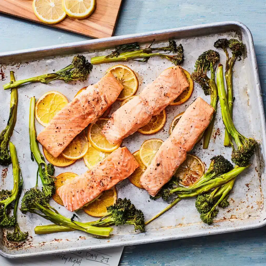 cooked salmon on a tray with broccoli on side