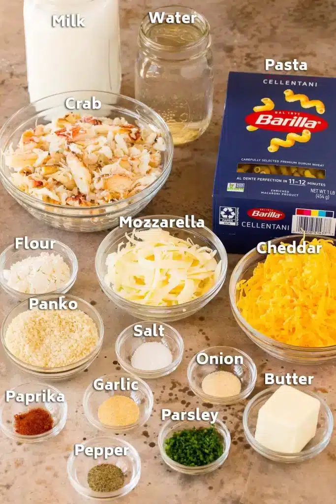 ingredients for crab mac and cheese pasta pack crab meat milk water spices onion parsley in small bowls