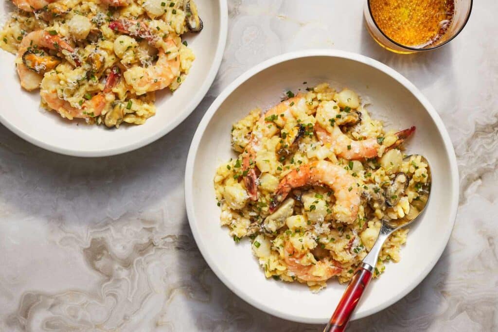 white plates with shrimp risotto placed on the marble countertop