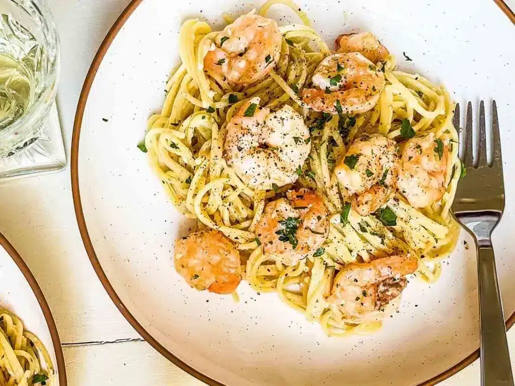 creamy shrimp scapmi garnish with parsely and served with spaghetti