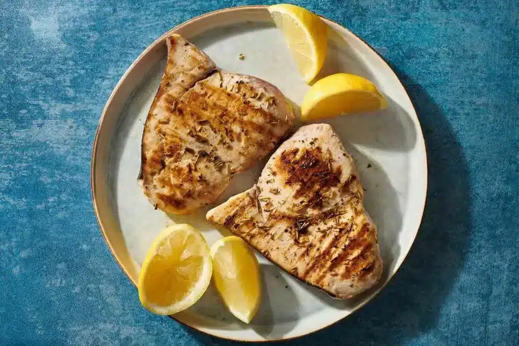 grilled swordfish steak served with lemon wedges 