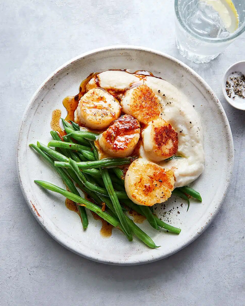 scallops along with a beans and mshed potato served in a plate