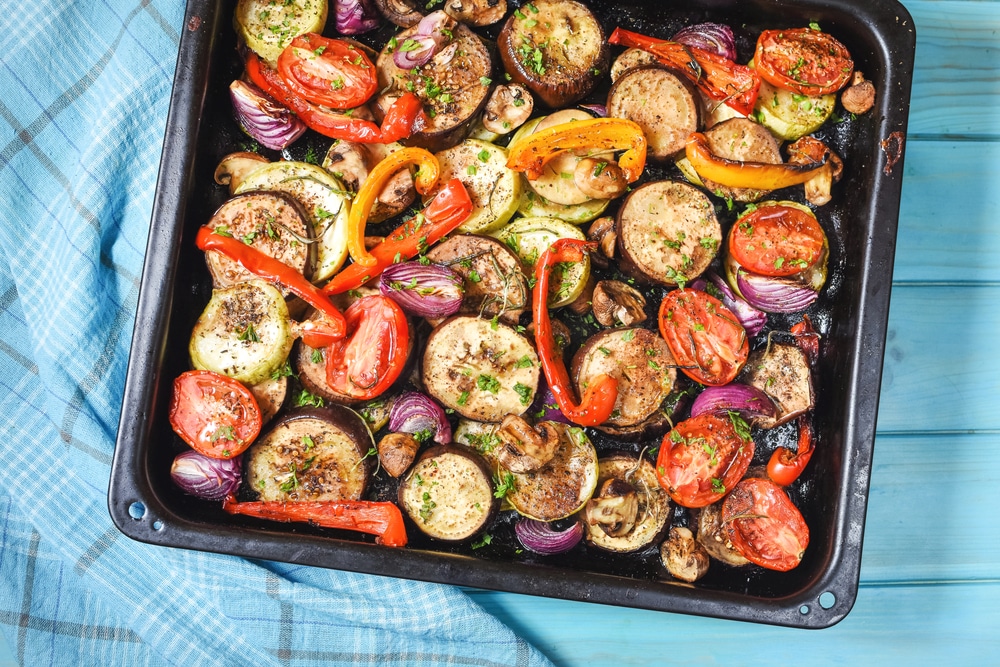 Roasted Vegetables Mix On Baking Tray On Blue Wooden Background