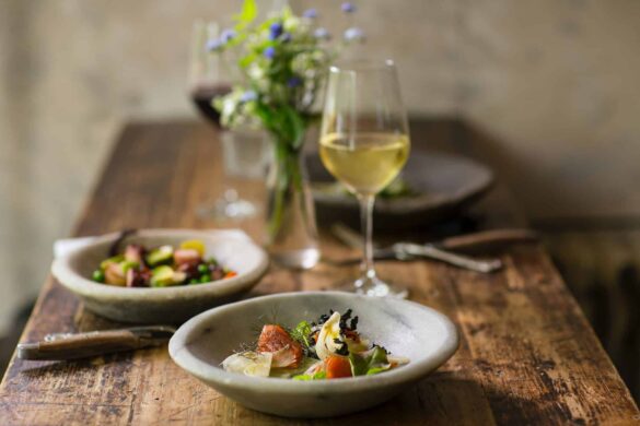 seafood dishes in plates and a glass of wine placed on a table seafood dishes in plates and a glass of wine placed on a table