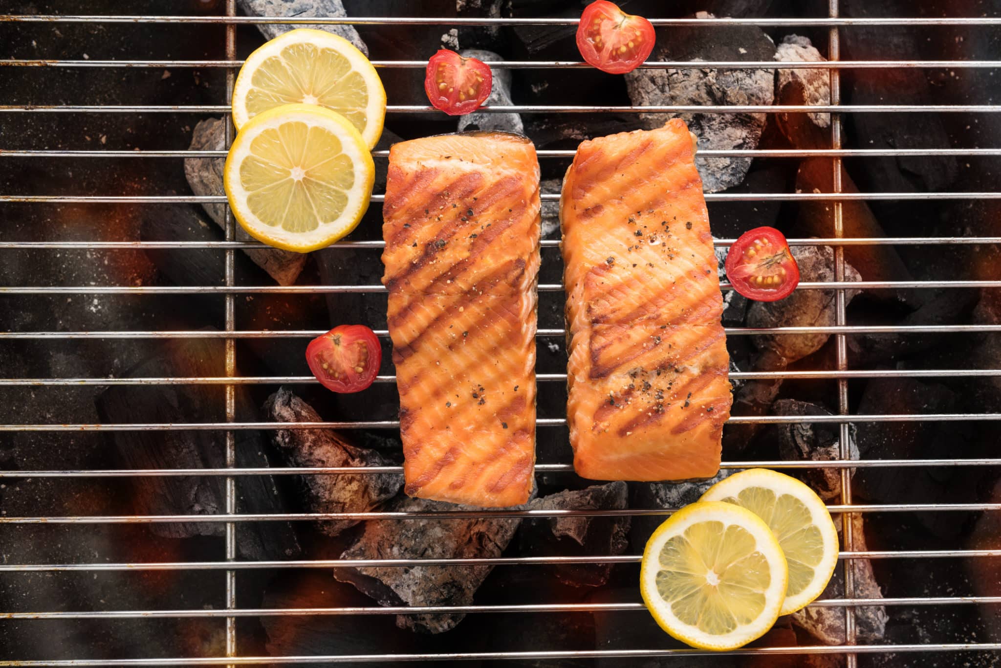 pieces of fish being grilled on a grilling pan lemon slices on the side